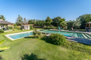 Un jardin avec une piscine, un petit abri de jardin et un kiosque.
