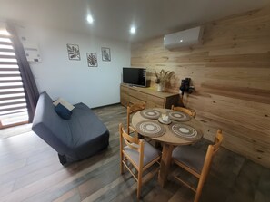 Un salon moderne comprenant un canapé, une table à manger avec des chaises, un téléviseur et des œuvres d’art décoratives accrochées au mur.