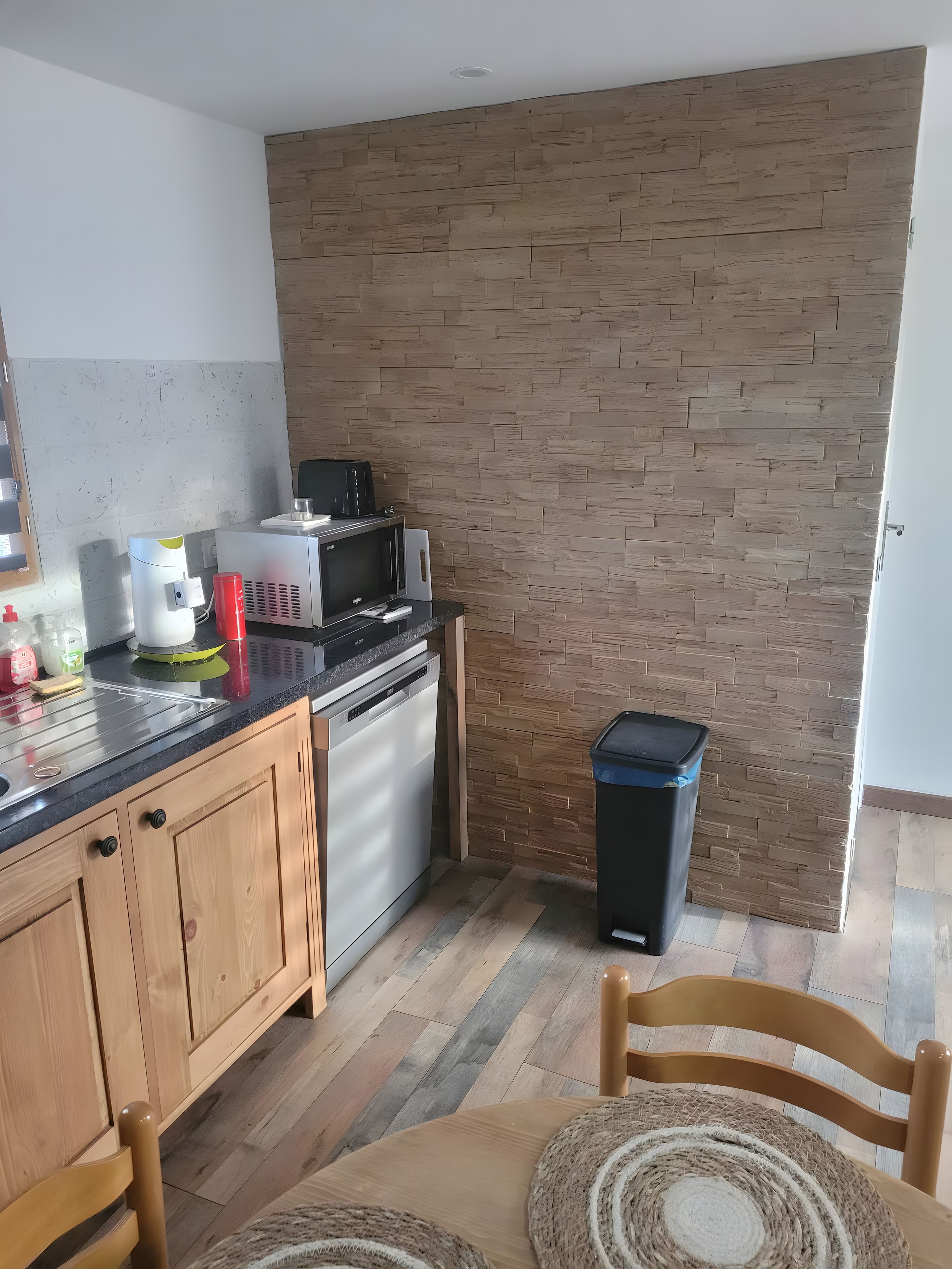 Una cocina equipada con lavavajillas, microondas y contenedor de basura.