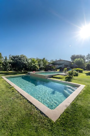 A rectangular swimming pool with clear blue water, surrounded by well-maintained grass and trees. - Gîte M with Shared Pools, Wi-Fi & Air Conditioning in Codognan (Codognan)