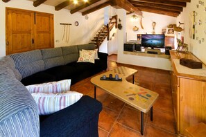 A cozy living room with a sofa, a coffee table, and a television. - Traditional Villa with Pool in Pollensa (Pollensa / Pollença)