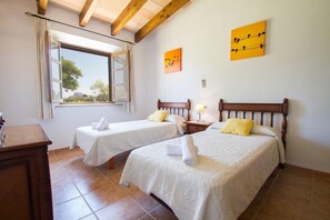 Ein Zimmer mit zwei Betten, einem Vorhangfenster und Bildern an den Wänden.