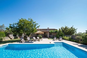 A swimming pool with lounge chairs, a stone building, and trees. - Stone Majorcan Villa with Gardens (Pollensa / Pollença)