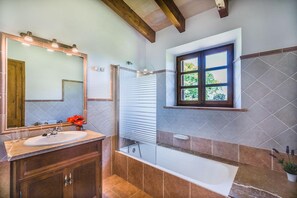 A bathroom with a bathtub, a sink, a mirror, and a window. - Stone Majorcan Villa with Gardens (Pollensa / Pollença)