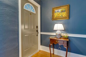 A hallway with a blue wall, a white door with a window, a lamp, a vase, and a framed picture. - Historic Downtown Stay on the Square (Lebanon)