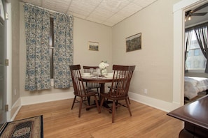 A dining area with a wooden table and chairs, a floral curtain, and two framed pictures on the wall. - Historic Downtown Stay on the Square (Lebanon)