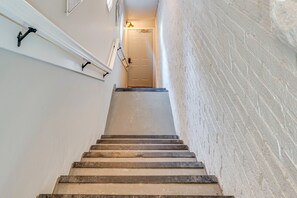 A staircase with a handrail, a door at the top, and a wall with a textured pattern.