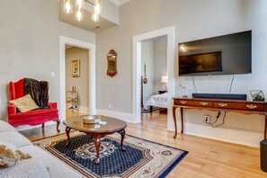 A living room with a red sofa, a coffee table, a TV, and a large mirror. - Historic Downtown Stay on the Square (Lebanon)