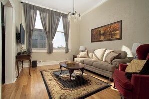 A living room with a sofa, a red armchair, a coffee table, a rug, and a painting on the wall.