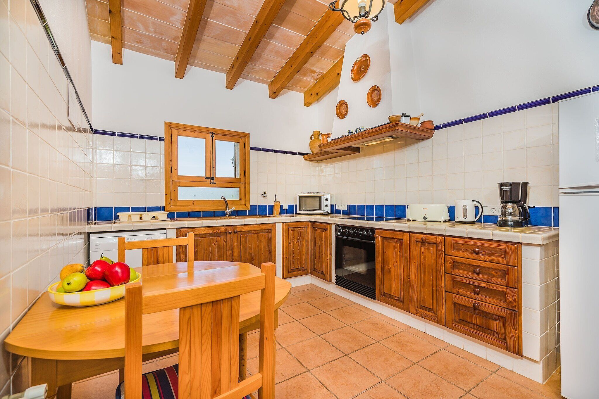 Une cuisine avec des meubles de rangement en bois, un pare-feu en carrelage, une cuisinière, un four à micro-ondes et une machine à café.