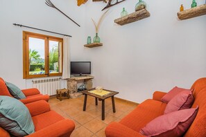 Ein Wohnzimmer mit orangefarbenen Sofas, einem Fernseher und einem Steintisch.