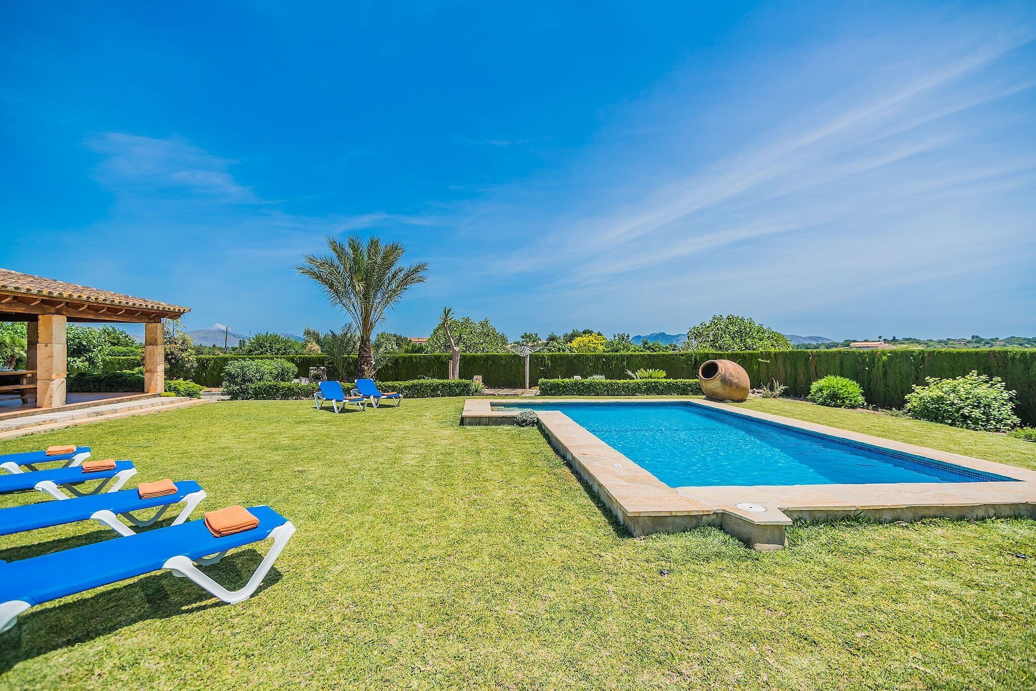 A swimming pool with a sun lounger area and a pergola.