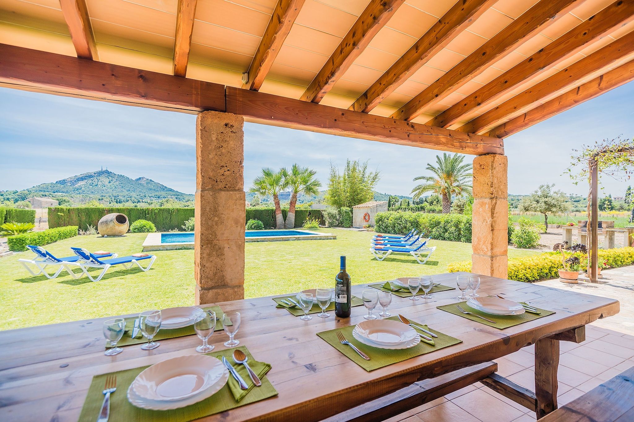 An outdoor dining area with a view of a swimming pool and hills.