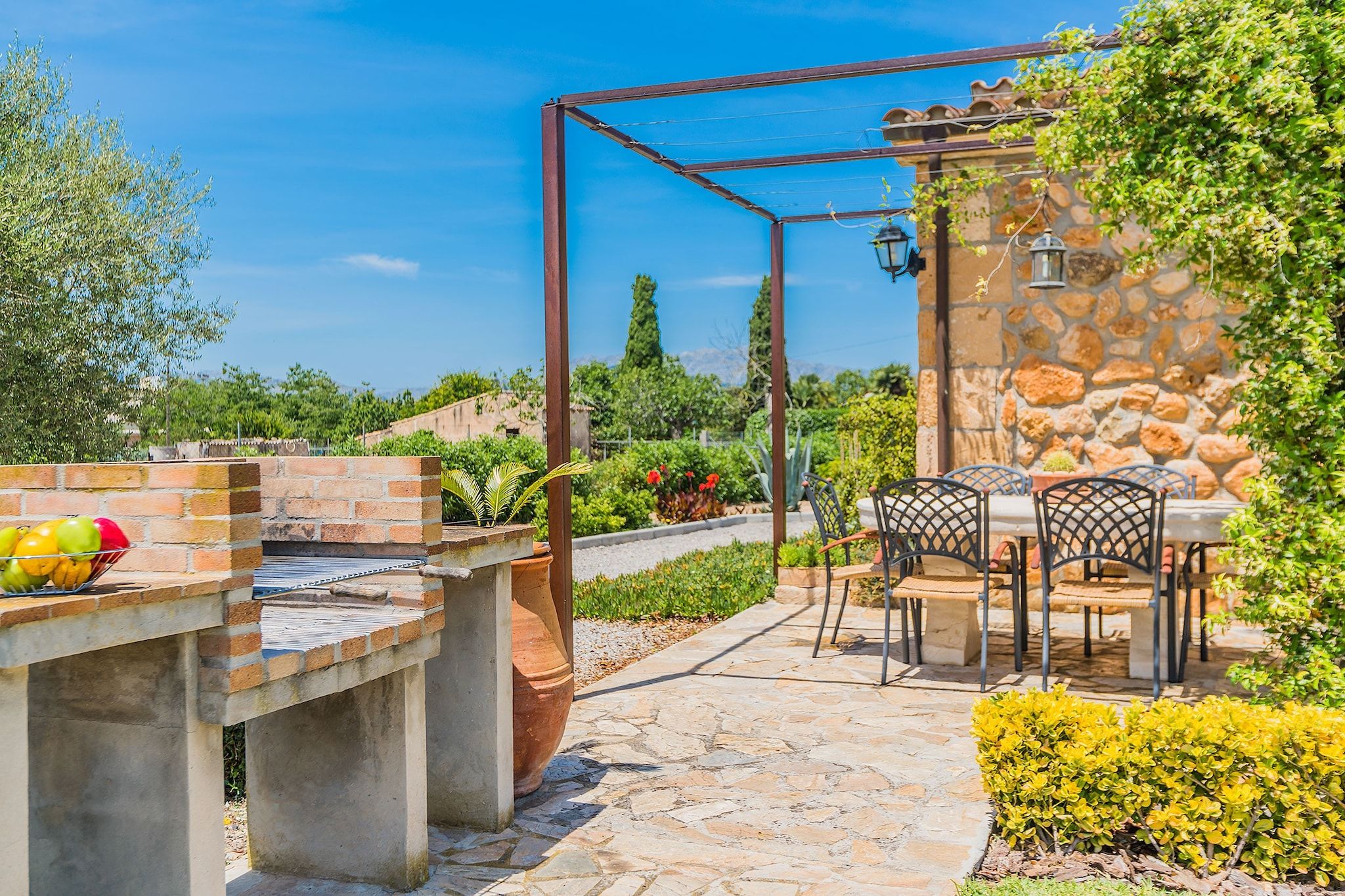 A patio with a barbecue grill, outdoor seating, and a stone wall.