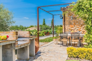Eine Terrasse mit Grill, Sitzgelegenheit und einer Steinmauer.