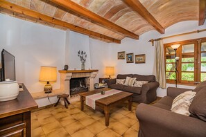 A cozy living room with a fireplace, two sofas, a coffee table, and a television. - Rustic Country Villa with Private Pool (Pollensa / Pollença)