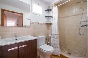 Un baño con lavamanos, inodoro, ducha y espejo.