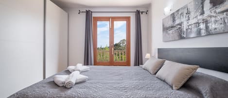A hotel room with a large bed, a view of the outdoors through a glass door, and a modern abstract painting on the wall.