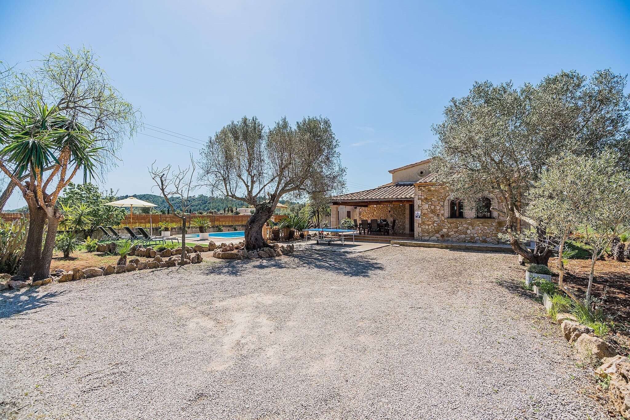 A house with a gravel driveway, outdoor seating area, and a pool.