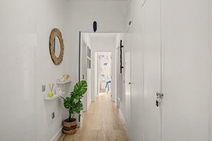 A hallway with a mirror, shelves, a potted plant, and a door leading to another room. - Vacation Apartment 'Danacris' with Private Terrace and Wi-Fi (Corralejo)