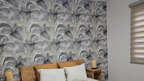 Una camera da letto con un letto, un comodino, una lampada e una finestra con persiane.