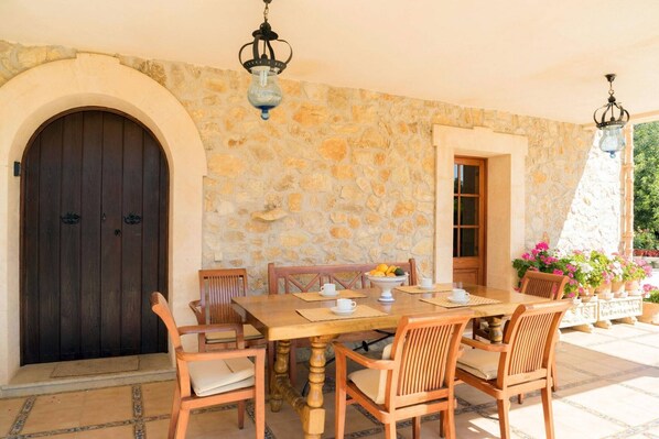 Habitació de paredats de pedra amb una porta de fusta, una taula de dinar amb cadires i lluminàries penjants.