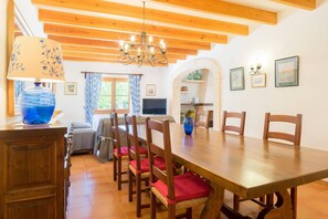 A dining area with a wooden table, chairs, and a chandelier. - Scenic Country Haven with Pool (Pollensa / Pollença)