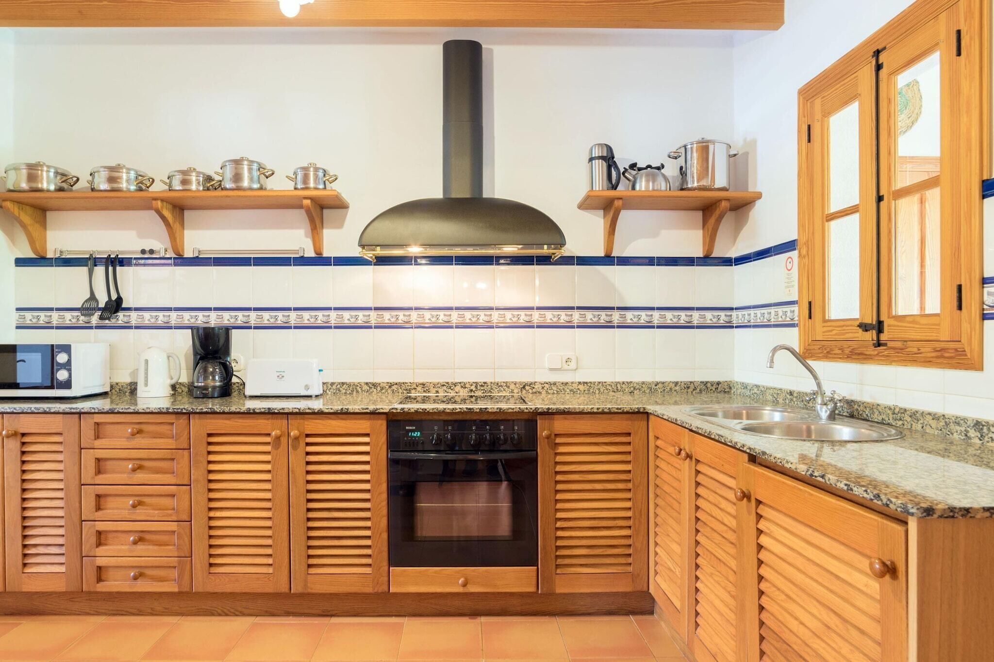 A kitchen with wooden cabinets, a Bosch oven, a microwave, and a coffee maker.