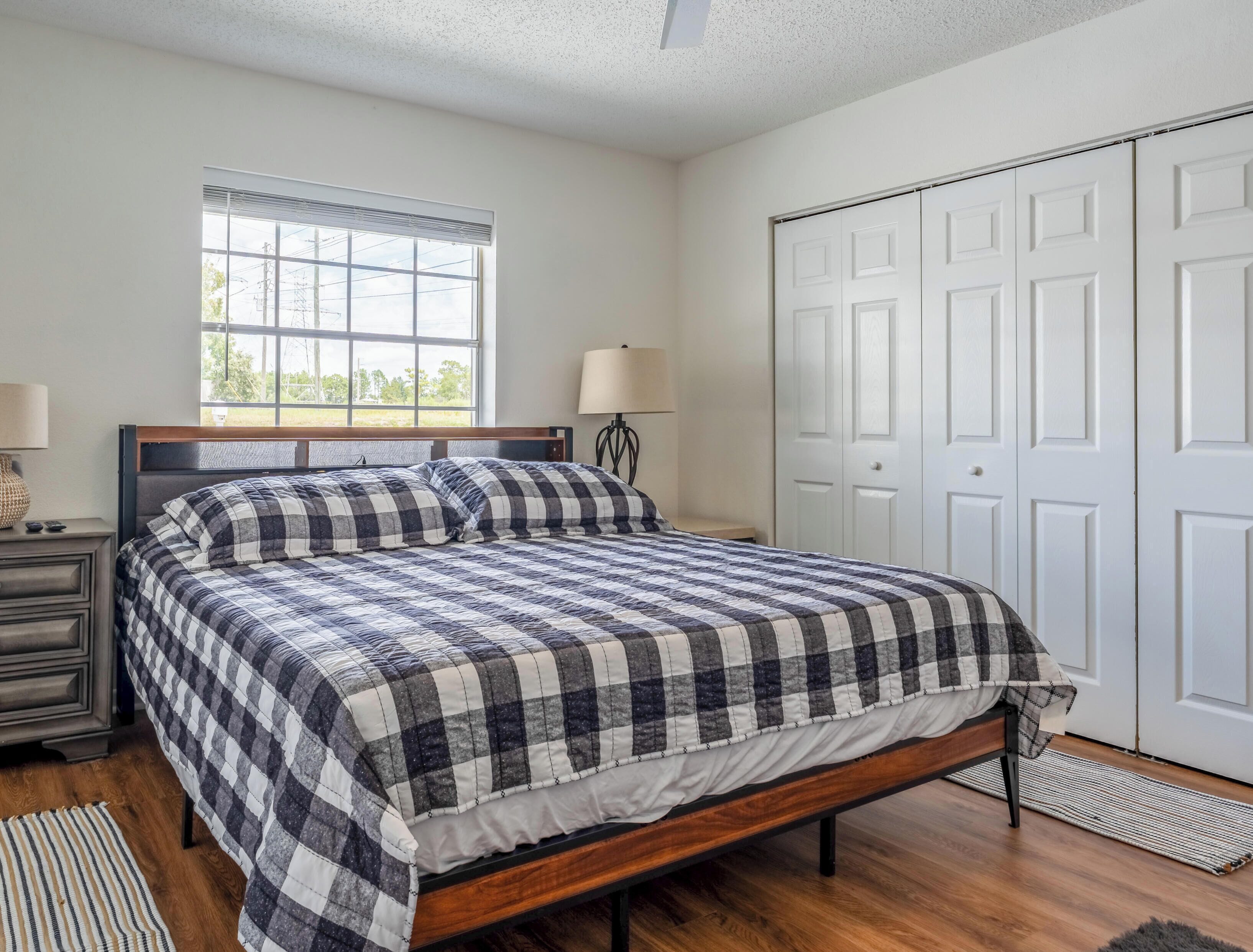 A bedroom with a bed, bedside lamps, a window, and a wardrobe.