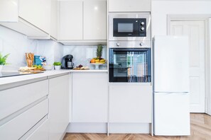 A modern kitchen with white cabinetry, a built-in oven, a microwave, and a coffee maker. - 3br 1 Bath Sleeps 7 Parking (Oldbury)