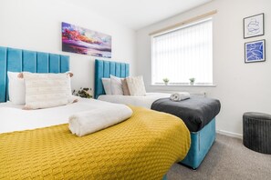 Ein Hotelzimmer mit zwei Betten, einem Fenster mit Jalousien und einem Kunstwerk an der Wand.
