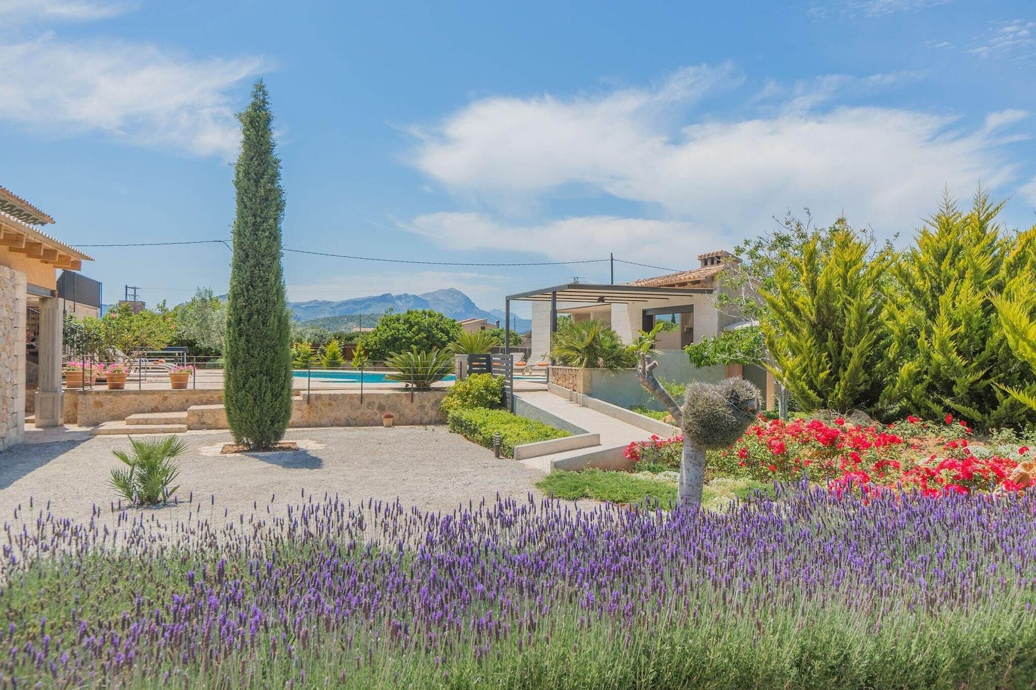 A residential property with a swimming pool, garden, and mountainous backdrop.