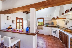 A kitchen with white cabinets, a wooden countertop, and a window overlooking greenery. - Country Villa with Garden for 6 (Pollensa / Pollença)