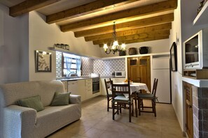 A cozy kitchen with a dining area, wooden beams, a chandelier, and a television. - Picturesque Country Villa for 6 (Pollensa / Pollença)