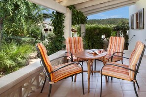 A covered patio with a table and four striped chairs, surrounded by greenery and a view of the landscape. - Picturesque Country Villa for 6 (Pollensa / Pollença)
