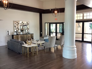 Un hall con un sofá, sillas, una mesa de centro, un espejo decorativo y un pilar grande.