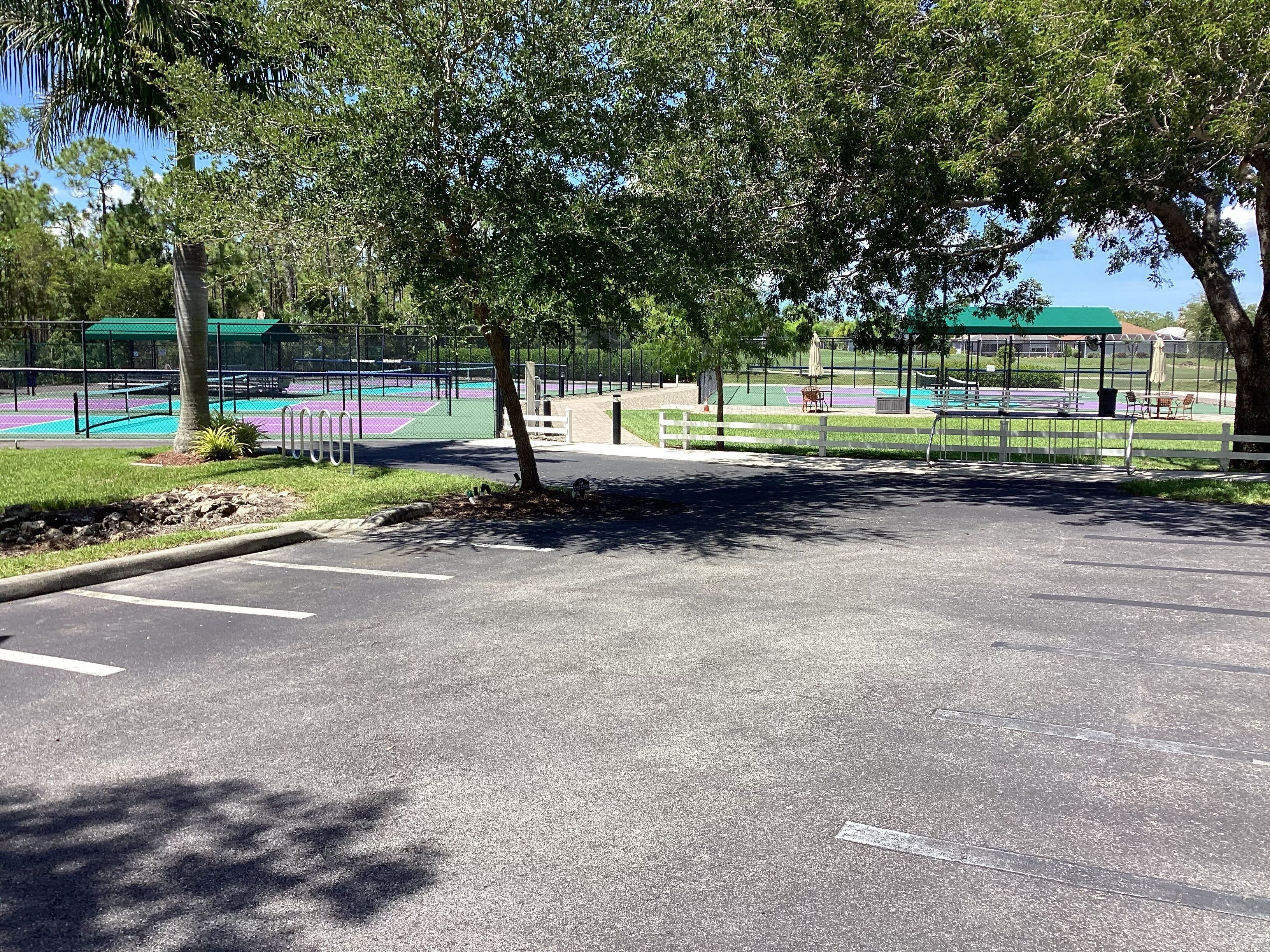 A parking area with a tennis court in the background.