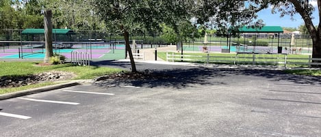 A parking area with a tennis court in the background.