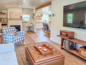 A living room with a fireplace, a television, and a bookshelf. - The Little House on Rocky Hill - Peaceful 2BR Newberg Wine Country Retreat (Newberg)