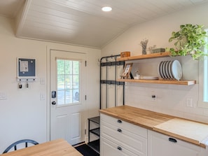 A kitchen with white cabinetry, a wooden countertop, and a hanging plant. - The Little House on Rocky Hill - Peaceful 2BR Newberg Wine Country Retreat (Newberg)