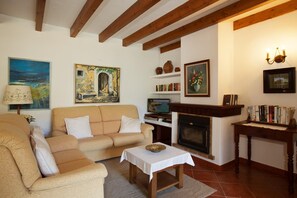 Un saló acollidor amb un sofà, una taula petita, una llar de foc i diversos objectes decoratius.