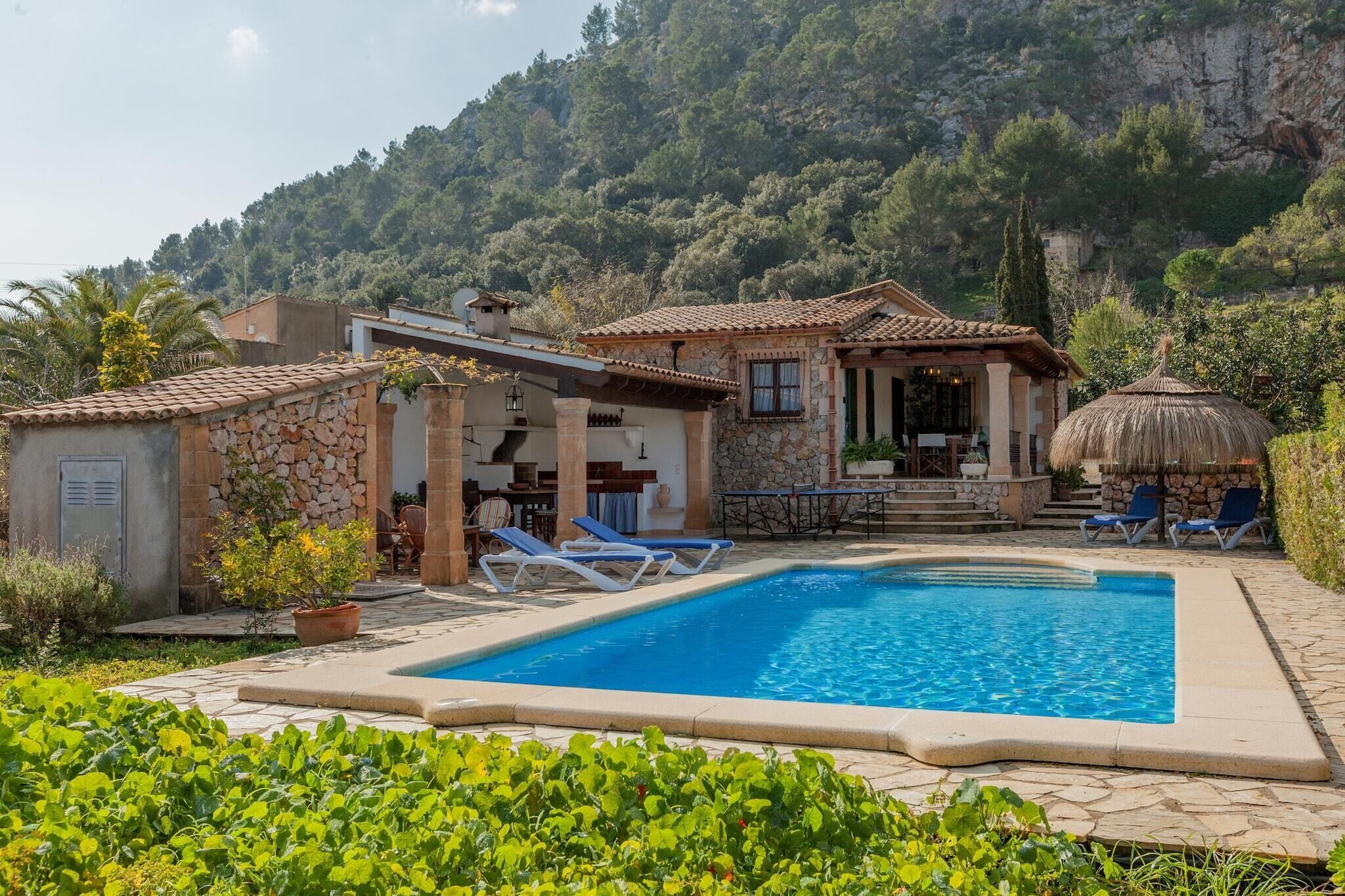 A villa with a swimming pool, outdoor seating, and a stone facade.