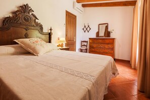A bedroom with a large bed, a wooden dresser, a chair, and a nightstand with a lamp. - Tranquil Pollensa Villa for 5 (Pollensa / Pollença)