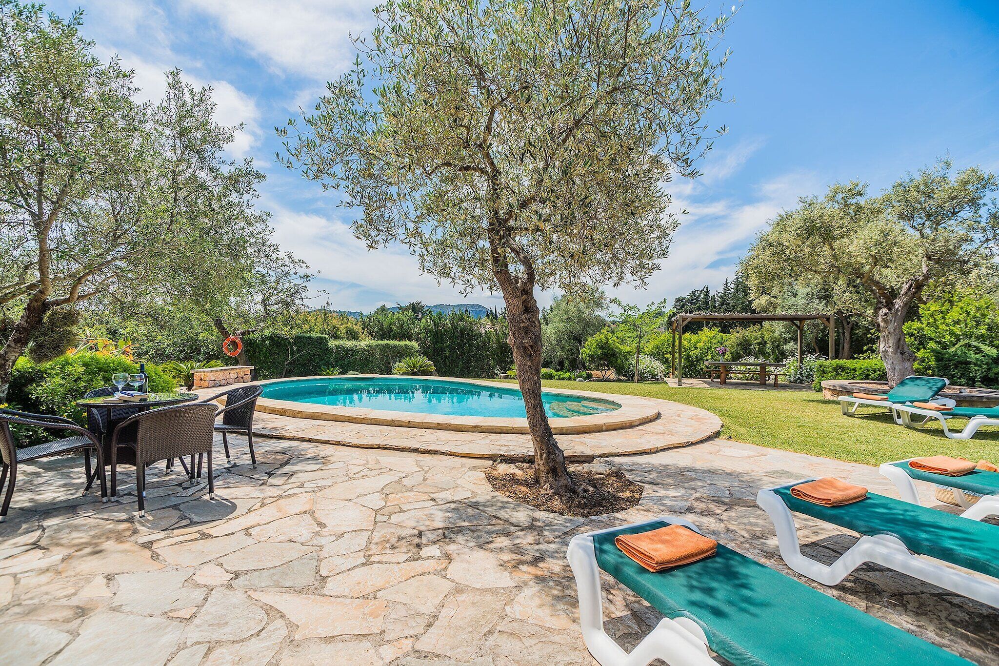 A pool area with lounge chairs, a table, and a pergola.