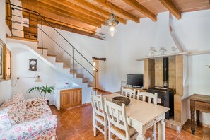A cozy living room with a wooden staircase, a dining area with a TV, and a fireplace. - Rustic Country Retreat for 4 (Pollensa / Pollença)