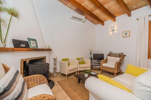 A cozy living room with a fireplace, comfortable seating, and a television. - Idyllic Country Getaway for 2 (Pollensa / Pollença)