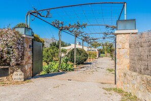 A gated entrance with a gravel path leading to a building, surrounded by vegetation and stone walls. - Idyllic Country Getaway for 2 (Pollensa / Pollença)