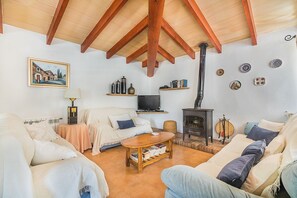 Ein gemütliches Wohnzimmer mit Kamin, Fernseher und bequemen Sitzgelegenheiten.