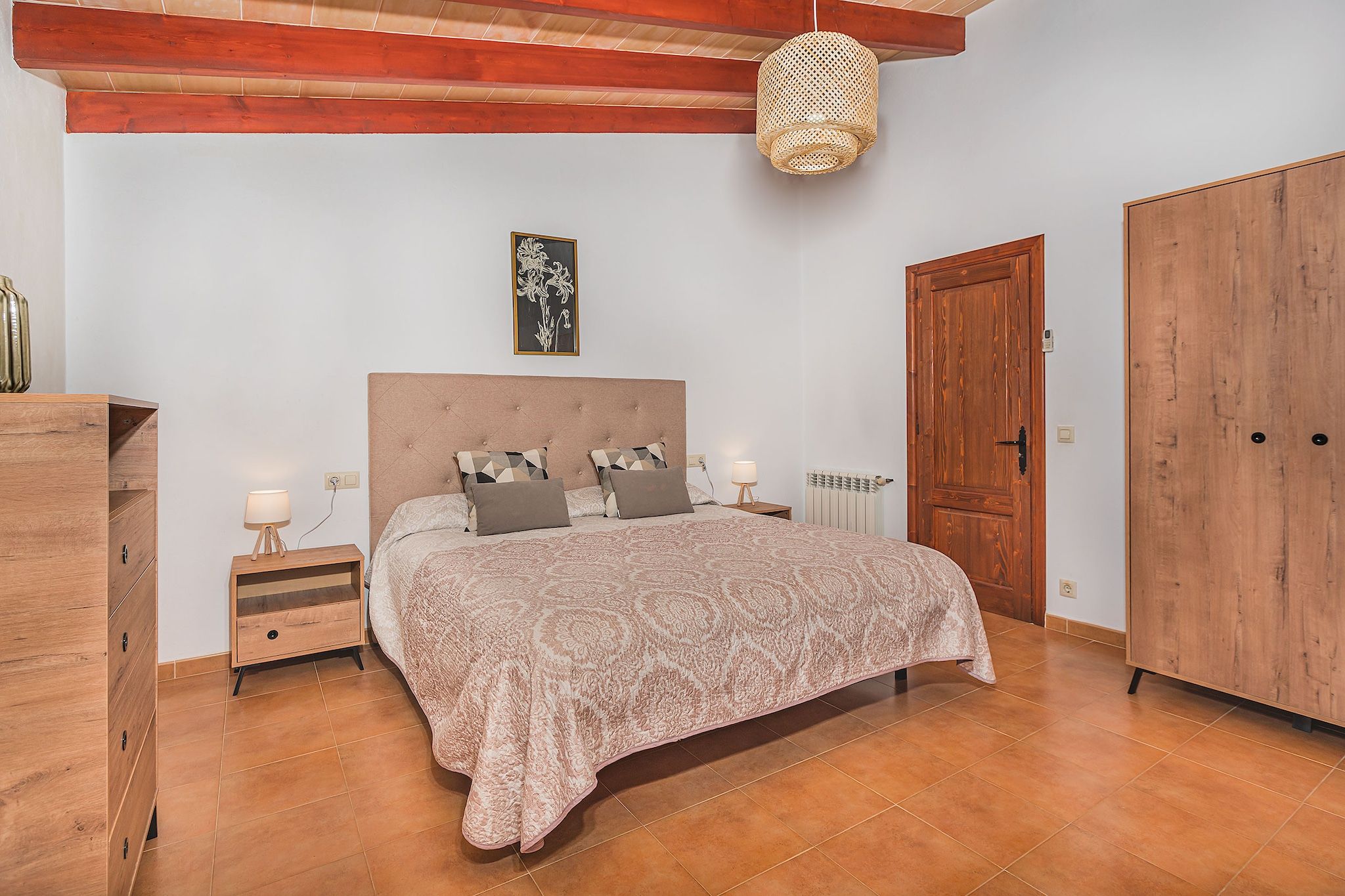 Ein Schlafzimmer mit Bett, Nachttischen, einem Kleiderschrank, einem Heizkörper und einer Hängeleuchte.