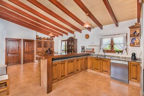 A spacious kitchen with wooden cabinets, a granite countertop, and a built-in dishwasher. - Single-Level Villa with Pool, Pollença (Pollensa / Pollença)